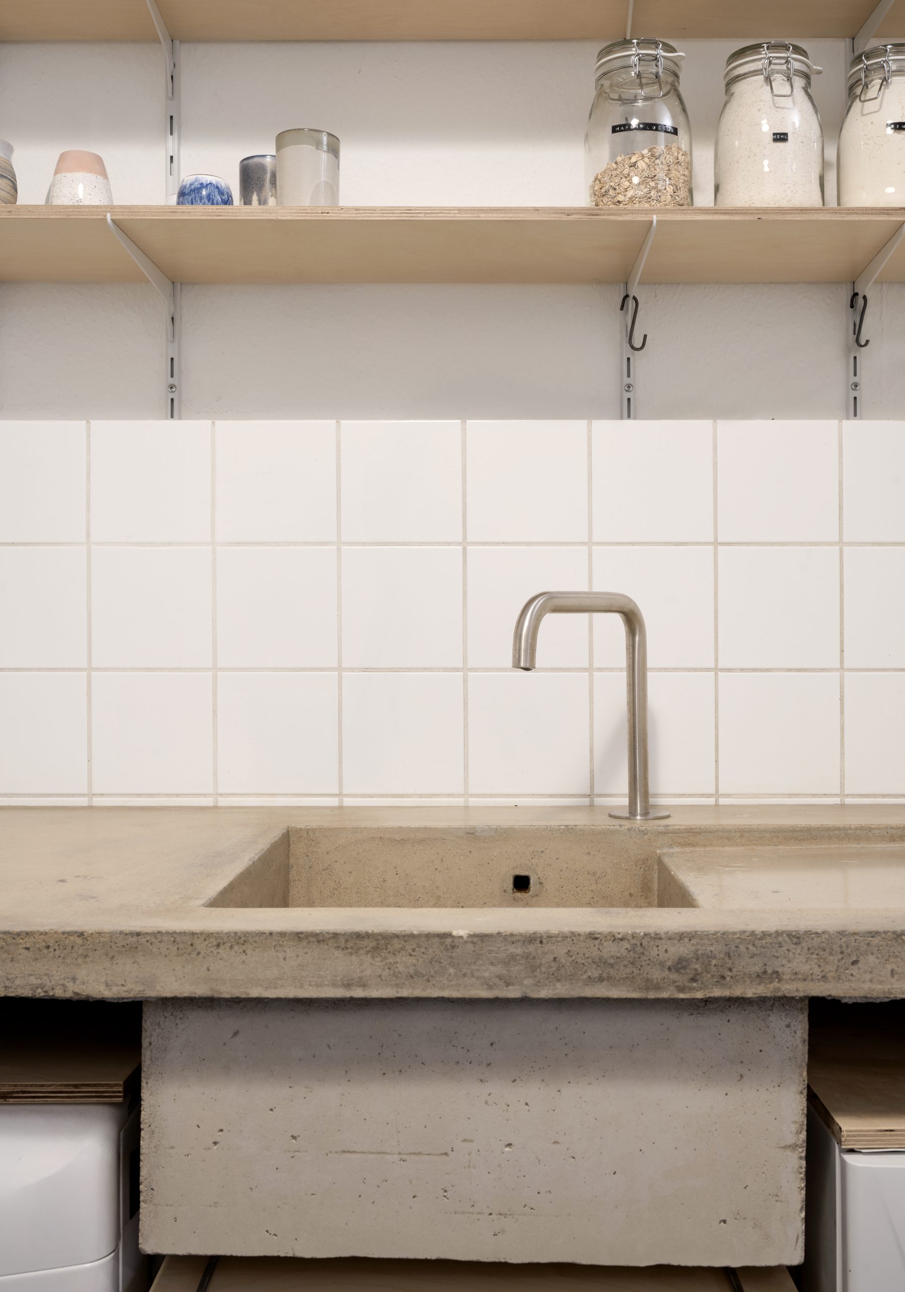 Frontale Hochformatansicht einer Betonarbeitsfläche mit integriertem Becken und Regalen darüber