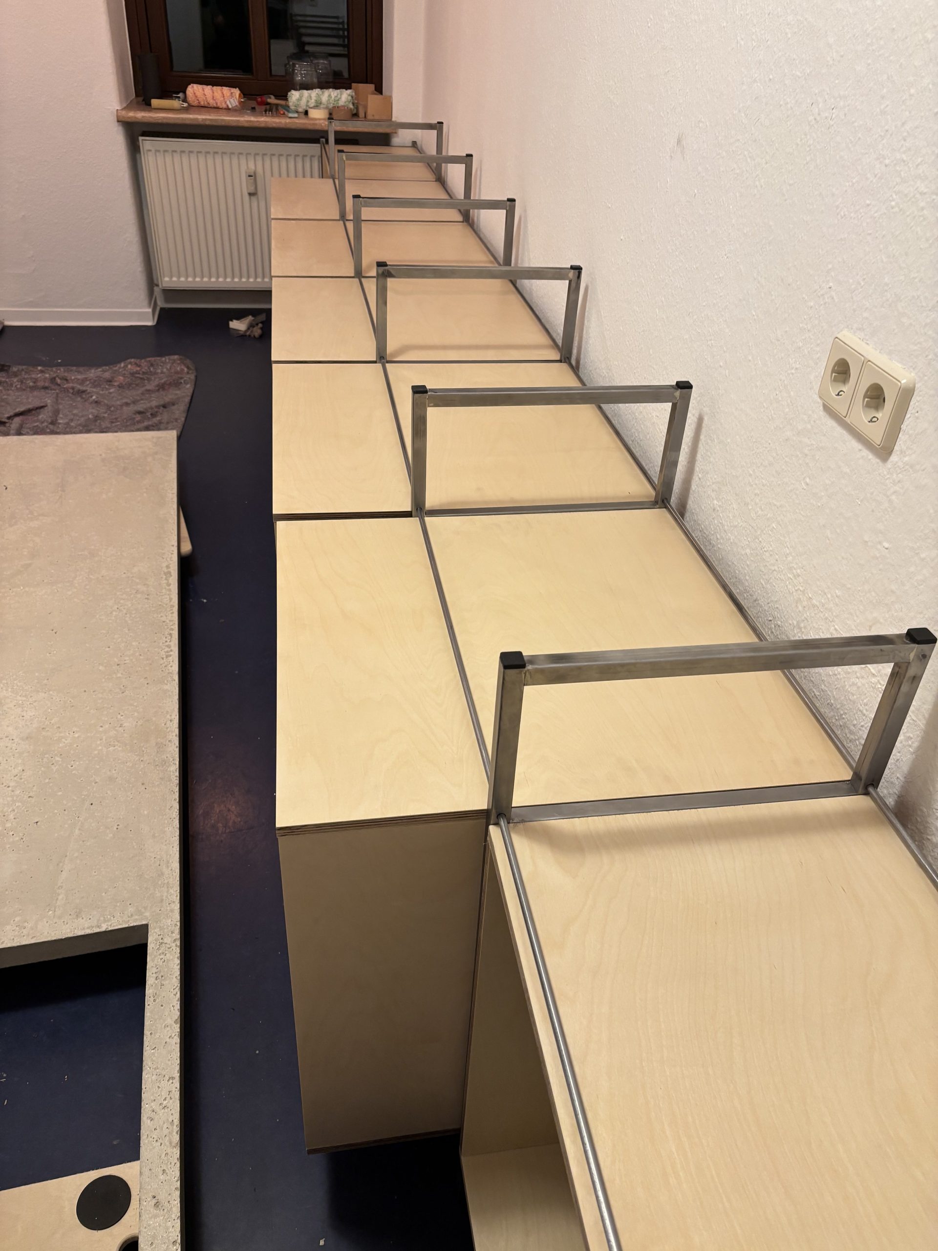 Holzkorpusse stehen in dem aus Rahmen und Stäben gebildeten Stahlgerüst