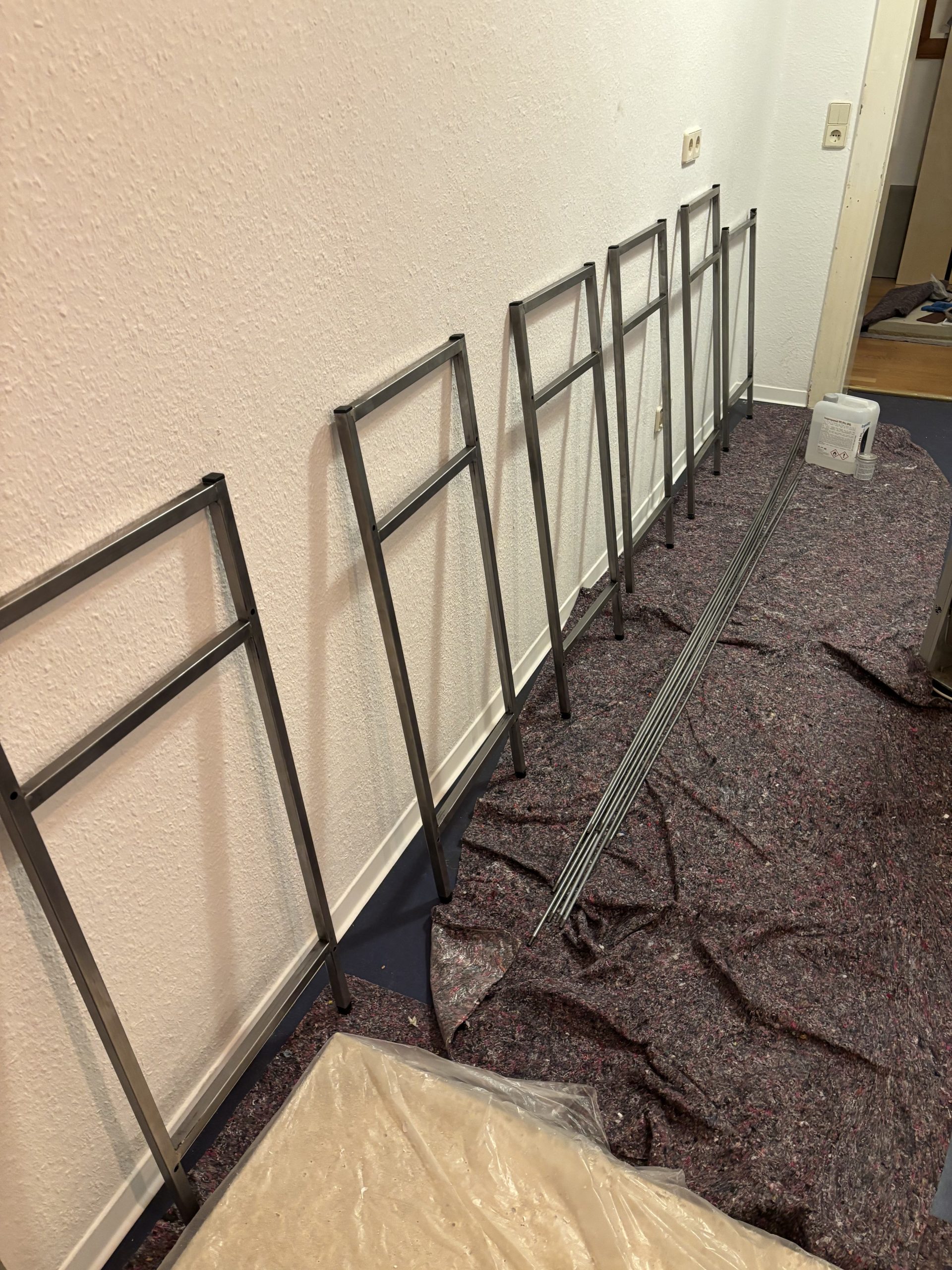 Einzelne Stahlrahmen stehen an der Wand neben einem Bündel loser Stahlstäbe