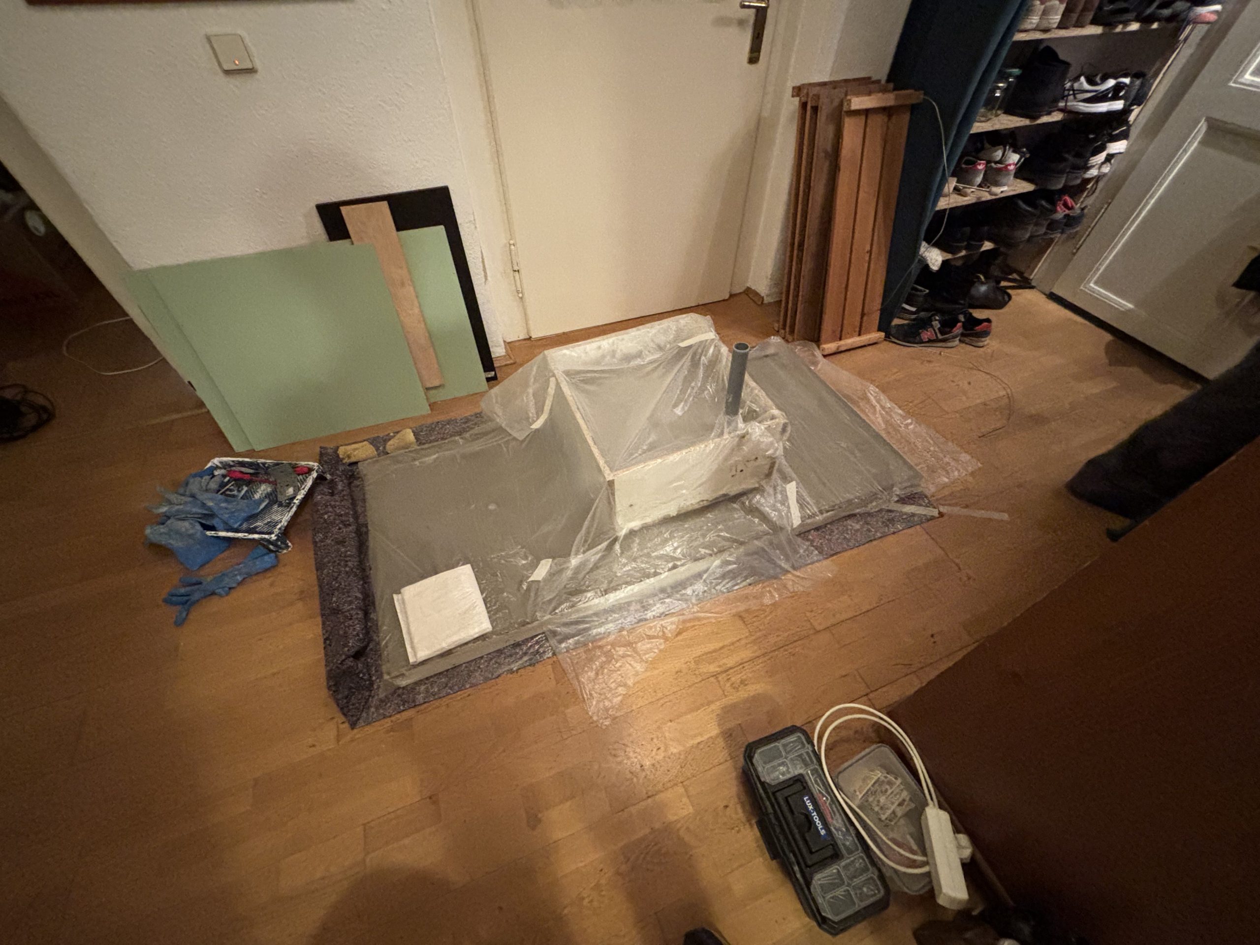 Frisch ausgeschaltes und teilweise mit Folie bedecktes Betonbecken mit Anschlussstutzen