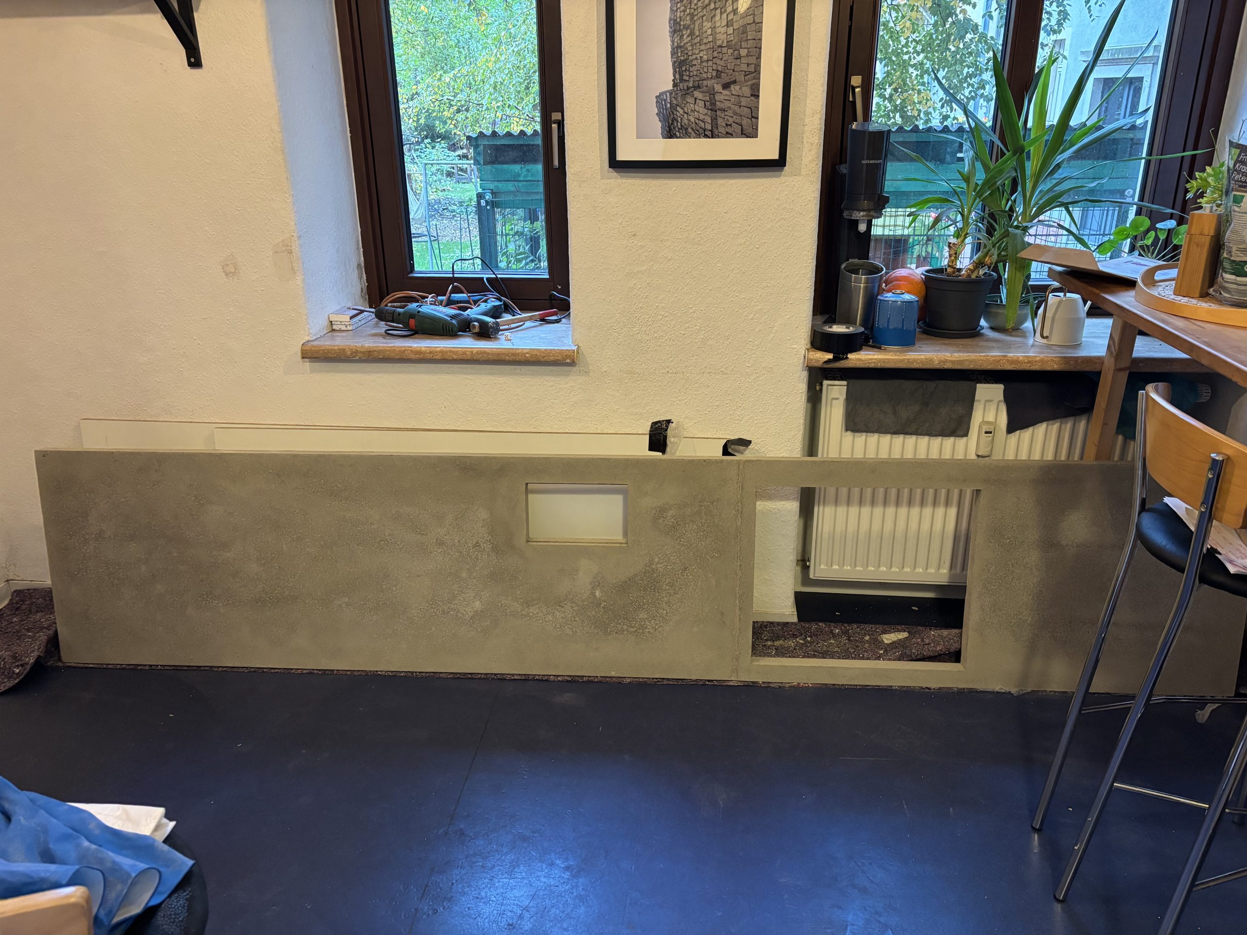 Großes ausgeschaltes Betonbauteil mit zwei Öffnungen steht an einer Fensterwand
